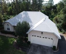 aerial view of new white shingles on white house in Orlando with very large bush in fron of the house