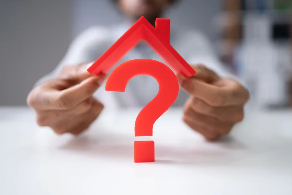 Someone holding a toy roof over a question mark, representing financing solutions for your home. 