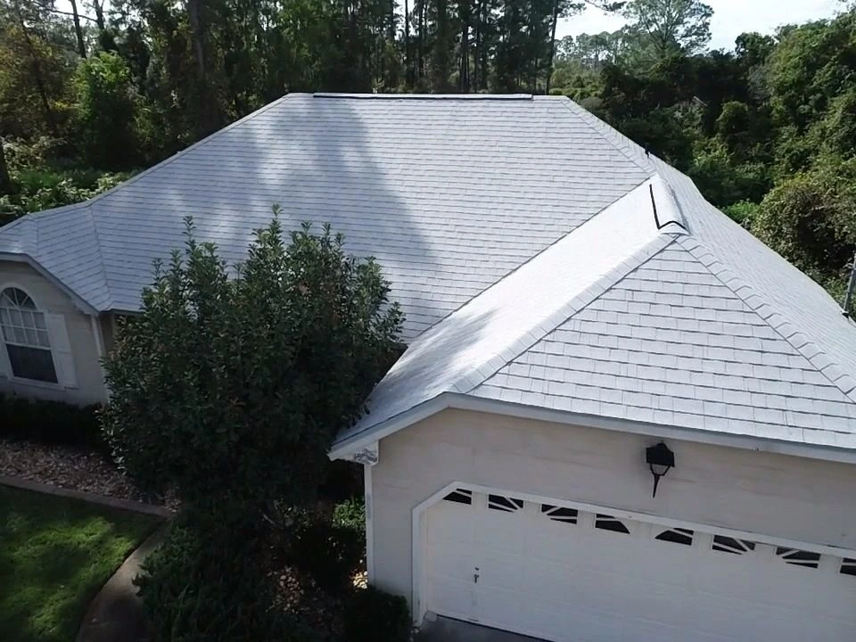 Aerial view of a white single story home with a new asphalt shingle roof and ridge vents installed by Nine Square Roofing.